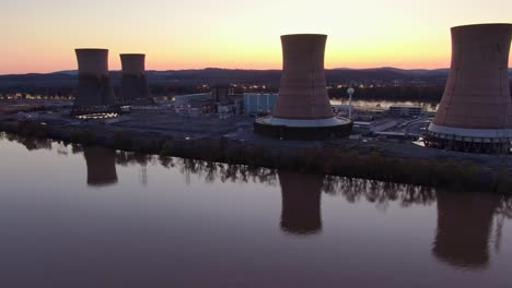 Aerial-pan-of-nuclear-power-plant-on-the-bank-of-a-river-in-sunset,-clean-and-environmentally-frinedly-production-of-electric-power,-green-energy-concept
