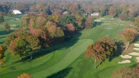 High-aerial-pan-reveals-expanse-of-country-club-golf-course-and-homes-during-autumn-morning-sunrise-in-Lancaster-PA