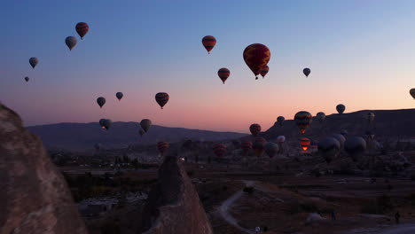 Aerial-dolly-in-shot-as-hot-air-balloons-launch-over-Goreme-Cappadocia-at-sunrise