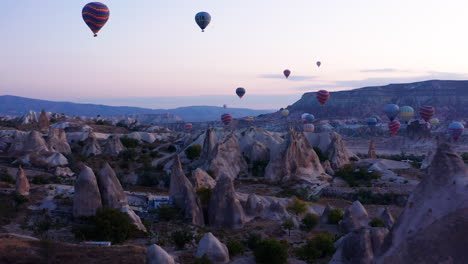 Dolly-in-shot-of-hot-air-balloons-flying-over-the-Fairy-Chimneys-in-Goreme-Cappadoica,-Istanbul,-Turkey