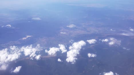 Slowly-and-steady-flying-over-the-clouds-in-high-altitude---view-on-landscape-under-them