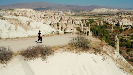 Woman-walking-towards-the-edge-of-a-cliff-in-Love-Valley,-Cappadocia,-Turkey