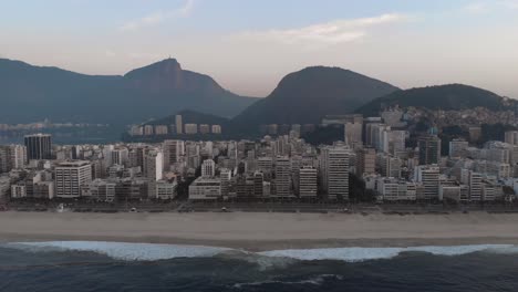 Aerial-view-of-empty-Ipanema-beach-with-city-lake-and-Corcovado-mountain-in-Rio-de-Janeiro-in-the-background-at-a-hazy-colourful-sunrise