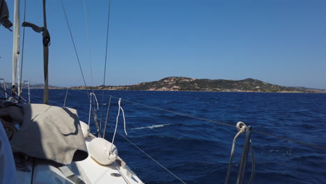 Wide-shot-from-a-sailing-boat,-cruise-in-deep-blue-water-with-a-island-in-the-background,-Sardegna,-Italy