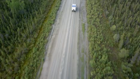 Top-down-shot,-RV-truck-driving-on-a-rough-road-in-spruce-forest