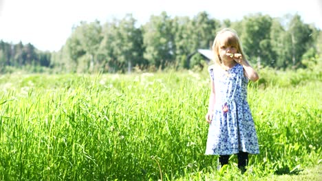 Girl-blowing-on-a-flower-on-a-windy-summer-day-in-front-of-a-field