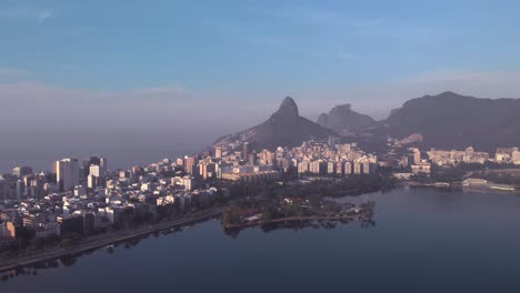 Aerial-approach-over-the-city-lake-towards-island-and-club-Caiçaras-in-Ipanema-in-the-foreground-and-Leblon-and-Two-Brothers-mountain-in-the-background-at-early-morning-sunrise
