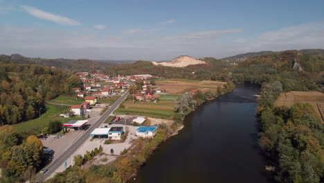Bosnia-road-through-remote-countryside-landscape-of-doboj,-rising-aerial-view-over-neretva-river