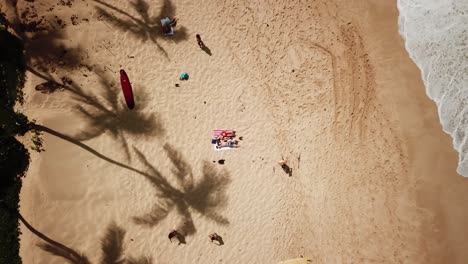 Aerial-view-of-a-happy-couple-on-their-honeymoon-laying-on-a-tropical-beach-in-Hawaii