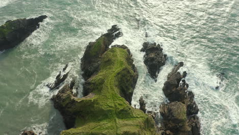 Aerial-top-down-view,-waves-crash-against-rocks-along-the-Irish-Coastline-in-Kerry