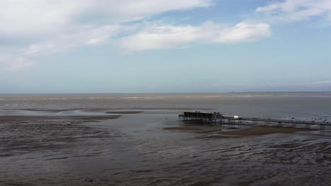 Lowering-aerial-drone-view-of-Southport-Pier-revealing-panoramic-landscape-of-empty-beach