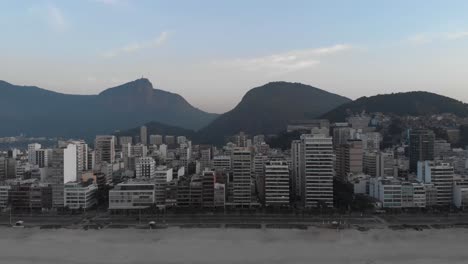 Luftaufnahme-Vom-Leeren-Strand-Von-Ipanema-Am-Frühen-Morgen,-Die-Meereswellen-Im-Vordergrund-Gegen-Das-Breitere-Stadtbild-Von-Rio-De-Janeiro-Mit-Dem-Corcovado-Berg-Im-Hintergrund-Enthüllt