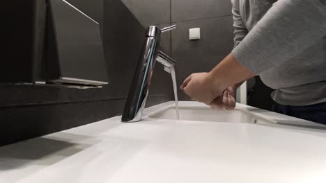 Der-Mann-Wäscht-Sich-Die-Hände-Am-Waschbecken,-Ein-Modernes-Badezimmer-In-Grauen-Farben-Und-Einem-Weißen-Waschbecken,-Statisches-Video