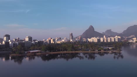 Aerial-panning-over-the-city-lake-with-island-and-club-Caiçaras-in-Ipanema-in-the-foreground-and-Leblon-and-Two-Brothers-mountain-in-the-background-at-early-morning-sunrise