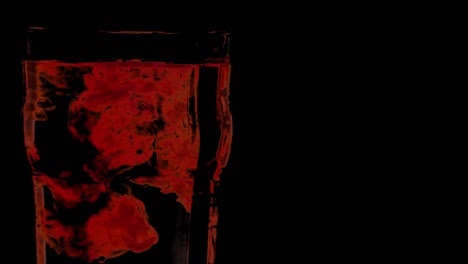 Rote-Tropfen-Im-Wasserglas-Mit-Schwarzem-Hintergrund