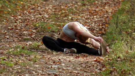 A-woman-doing-warm-up-stretches-before-going-for-a-run-through-a-nature-reserve