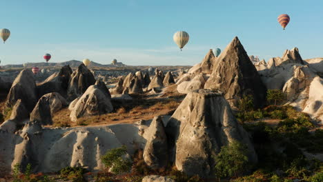 Reveal-shot-flying-above-the-rock-formations-of-Goreme-Cappadocia-following-the-hot-air-balloons