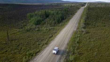 Aerial-view-of-adventure-RV-truck-driving-on-a-country-road-in-spruce-forest