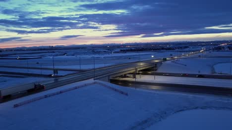 Dusk-aerial-of-snowy-overpass-with-lonely-traffic-and-evening-cloud