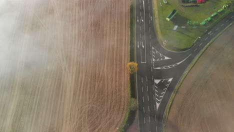 A-road-through-a-rural-agricultural-area-in-Luxembourg,-top-down-shot-of-a-morning-with-fog