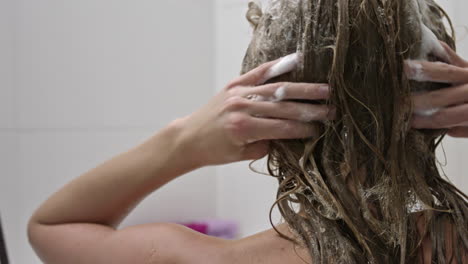Woman-in-bath-cleaning-her-long-blond-hair-with-shampoo-and-conditioner