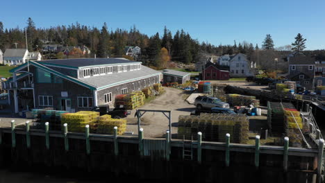 Aerial-Fly-By-Drone-Footage-of-man-dragging-Lobster-Traps-at-Lobster-Fishery-Warehouse-in-Vinalhaven,-Fox-Islands,-Knox-County-Maine,-USA