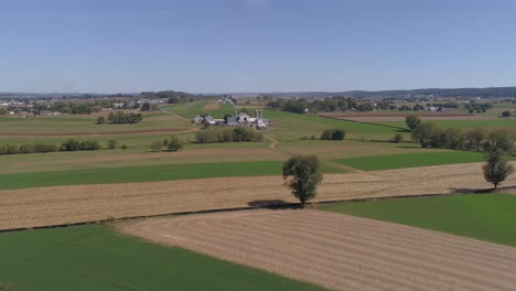 Aerial-View-of-Amish-Countryside-of-Farmer-Working-Field-by-a-Rail-Road-Track-as-a-Steam-Engine-Approaches-as-Seen-by-a-Drone