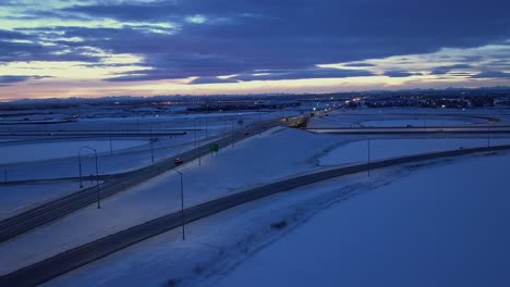 Vehicles-on-snowy-highway-overpass-at-dusk,-aerial