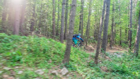 An-enthusiast-cyclist-riding-his-mountain-bike-through-the-uneven-terrain-amidst-dense-green-forest