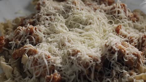Parmesan-cheese-falling-on-Fusilli-pasta-with-meat-sauce,-slow-motion