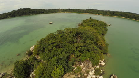 Aerial-of-a-tiny-tropical-island-with-white-sand,-with-large-rocks-and-jungle