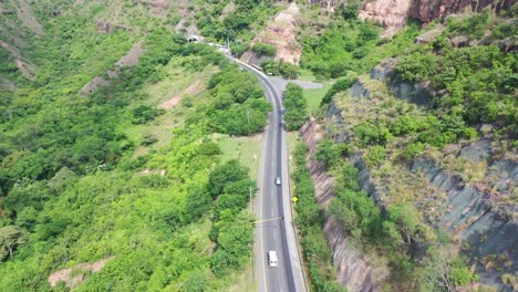 Aerial-shot,-following-a-car-for-a-road-until-arrives-to-the-terowogan-in-Colombia-with-wonderful-colors-green-and-the-grey-of-the-road,-is-a-road-inside-the-pegunungan