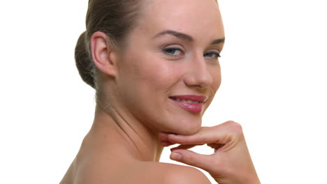 A-close-up-of-a-woman's-face-smiling-and-laughing,-head-tilting-back-with-her-hand-brushing-her-face,-on-a-seamless-white-studio-background