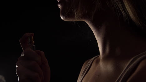 Zeitlupenvideo-Einer-Frau,-Die-Parfüm-Auf-Ihren-Hals-Auf-Schwarzem-Hintergrund-Sprüht