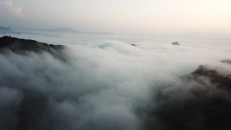 Nubes-Sobre-El-Valle-Bajo-Los-Picos-De-Las-Montañas-En-El-Crepúsculo-En-El-Centro-De-Laos,-Vista-Aérea-De-Gran-Altura