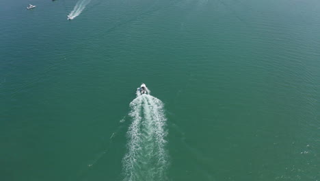 Speedboat-sailing-on-open-sea-and-approaching-other-boats,-yachts,-aerial-shot
