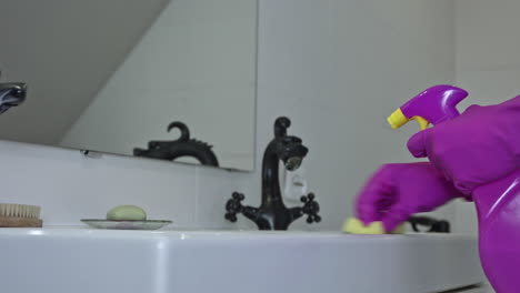 A-woman-in-rubber-gloves-cleans-the-sink-with-a-sponge-and-spray