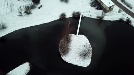 Top-down-drone-shot-on-solitude-frozen-island-in-a-small-lake---FLY-UP