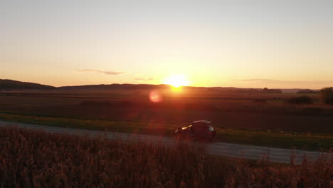 Road-trip-through-countryside-at-sunset,-aerial-arc-shot