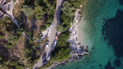 Car-driving-on-coastal-road-in-Mediterranean,-high-angle-above