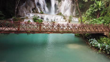 Exotic-Heavenly-Scene,-Static-Aerial,-Wooden-Bridge-Under-Amazing-Waterfall-in-Laos,-Kuang-Si-Falls