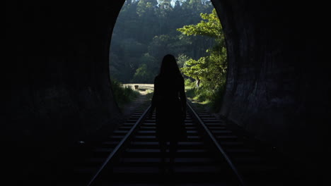 Eine-Junge-Frau-Geht-Auf-Den-Bahngleisen-Durch-Einen-Tunnel-Dem-Tageslicht-Entgegen