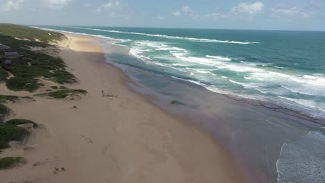 Schwenkende-Luftaufnahme-Des-Riesigen-Chidenguele-strandes-In-Mosambik-Mit-Dünen-Und-Tosenden-Wellen