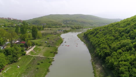 People-Kayaking-in-peaceful-river-Drin-in-Kosovo,-Aerial-flyover-shot