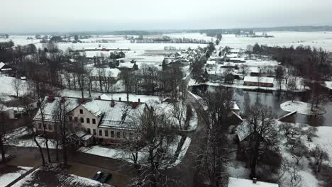 Long-aerial-drone-dolly-over-calm-winter-village,-farmland-and-rural-countryside
