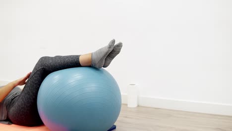 a-young-Caucasian-woman-performing-a-corrective-exercise-using-a-physio-exercise-ball-in-a-sports-physiotherapy-clinic