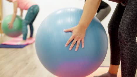 Young-women-performing-bend-over-rows-exercise-for-shoulder-and-arm-stability-using-a-physio-exercise-Swiss-ball-in-a-sports-physiotherapy-clinic,-close-up