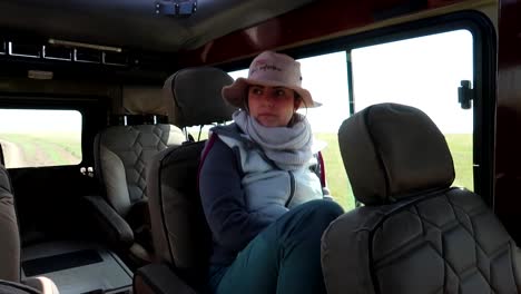 Young-woman-on-safari-traveling-in-a-4x4-jeep,-looking-and-smiling-into-the-camera,-enjoying-the-honeymoon