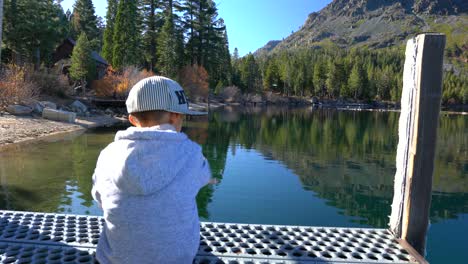 Child-stretching-out-his-arms-as-he-looks-out-into-a-beautiful-lake-scenery