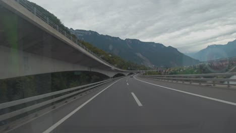 Capturing-a-scenic-view-of-mountains-and-city-while-driving-through-the-motorway-of-Slovenia-from-the-car-front